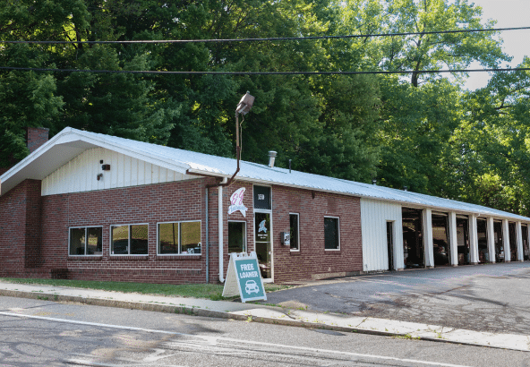 A red-bricked car wash building with a "Free Vacuums" sign outside and multiple open garage bays.