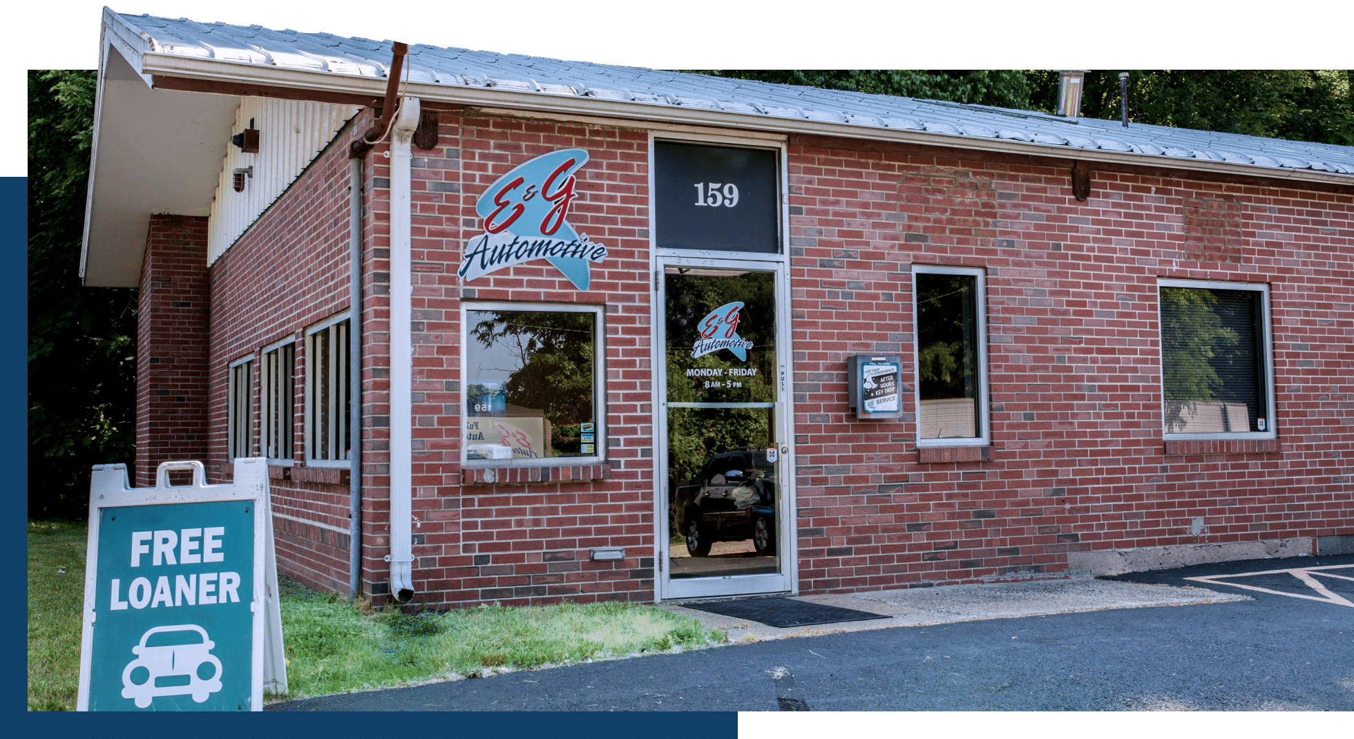 A brick building with "E & J Automotive" on the sign and a "FREE LOANER" sign in front. The door is marked with number 159.